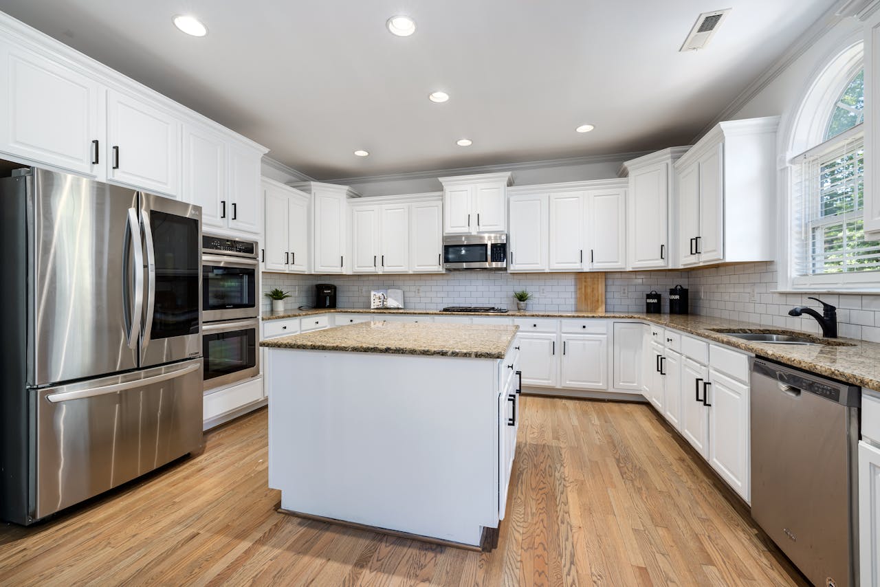 Modern kitchen featuring white cabinets, granite countertops, and stainless steel appliances.